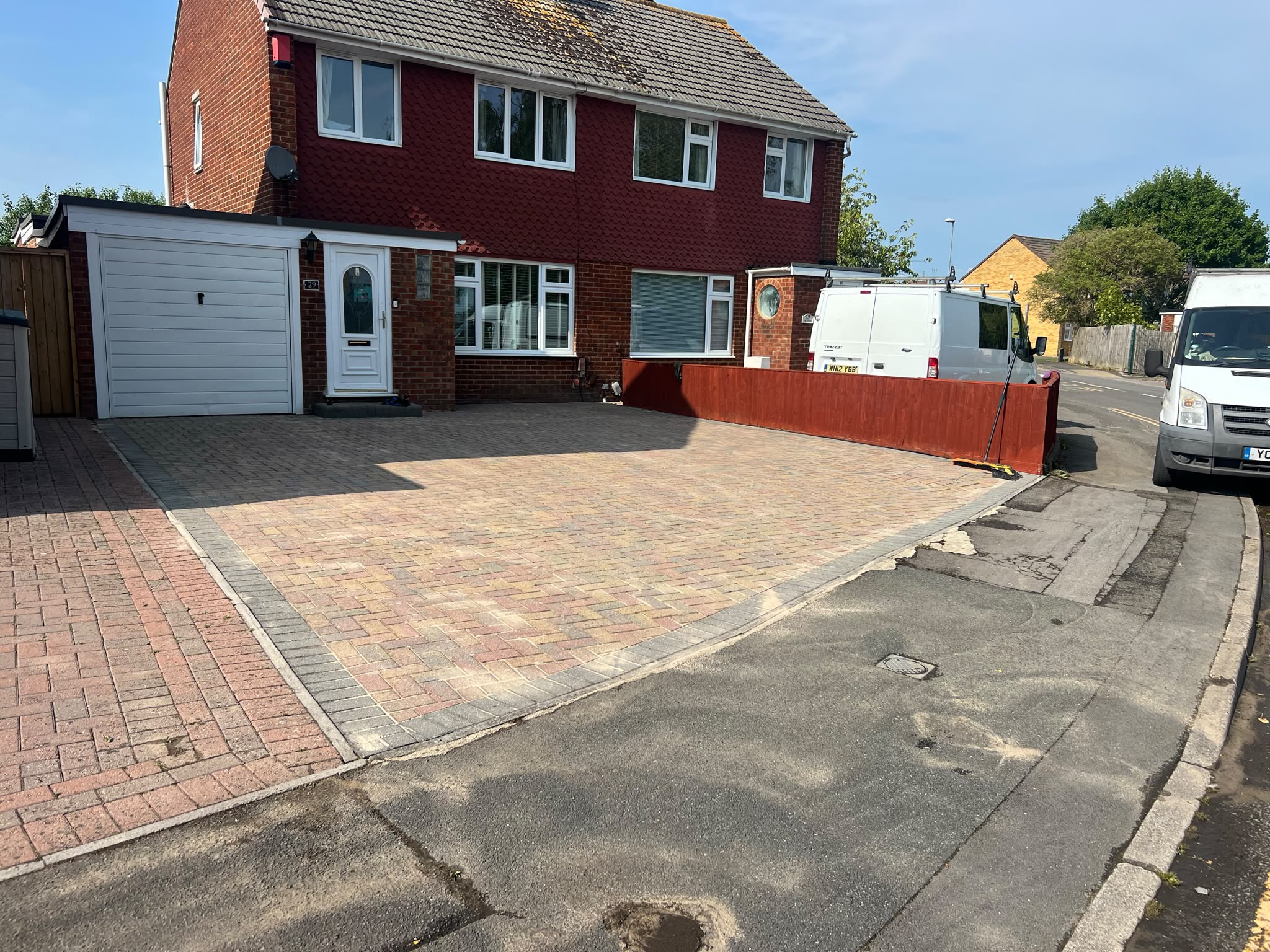 Fresh multi-tone herringbone block paving driveway with charcoal edging in front of a red brick house